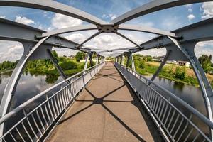 Eisenstahlrahmenkonstruktion der Fußgängerbrücke über den Fluss. Weitwinkelansicht foto