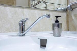 Wasserhahn Waschbecken mit Wasserhahn im teuren Loft-Badezimmer. Detail einer Eckduschkabine mit wandmontierter Duschvorrichtung foto