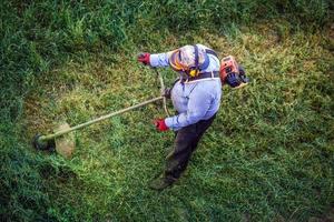 draufsicht fetter schmutziger rasenmäher mann arbeiter schneiden trockenes gras mit rasenmäher. foto