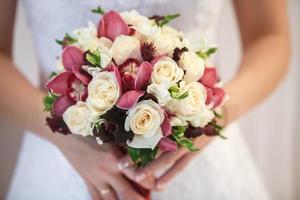 Hochzeitsstrauß aus weißen und rosafarbenen Pfingstrosen und Rosen in Brauthänden foto