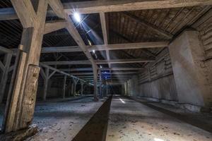 im dunklen, verlassenen, ruinierten, verfallenden Hangar aus Holz mit verrottenden Säulen foto