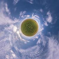 kleiner Planet im blauen Himmel mit Sonne und schönen Wolken. Transformation des sphärischen Panoramas 360 Grad. sphärische abstrakte Luftaufnahme. Krümmung des Raumes. foto