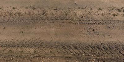 Blick von oben auf die Textur der Schotterstraße mit Autoreifenspuren foto