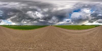 Vollständiges nahtloses sphärisches Hdri-Panorama 360-Grad-Winkelansicht auf nasser Schotterstraße zwischen Feldern am Frühlingstag mit Gewitterwolken nach Regen in äquirechteckiger Projektion, bereit für vr ar-Inhalte foto