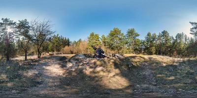 Vollkugelförmiges HDRI-Panorama 360-Grad-Winkelansicht auf Schotterfußweg und Radweg im Kiefernwald in der Nähe der Kanone des Ersten Weltkriegs in equirectangularer Projektion. vr ar-Inhalt foto