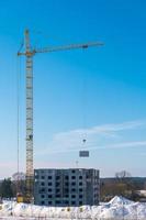 turmkräne und unvollendete mehrstöckige hoch in der nähe von gebäuden im bau an sonnigen wintertagen foto