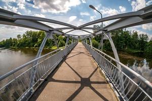 Eisenstahlrahmenkonstruktion der Fußgängerbrücke über den Fluss. Weitwinkelansicht foto