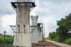 Infrastrukturkonstruktionskonzepte, Bau der Autobahnlinie im Gange mit schwerer Infrastruktur, Brückenbaustelle mit Kran, der vorgefertigte Betonrahmen hebt foto