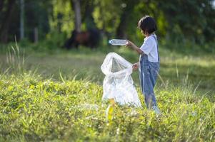 asiatische kinder packen freiwillig plastikflaschen in müllsäcke. Freiwilligenkonzept und Ökologie foto