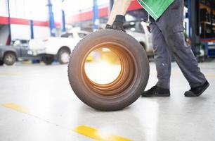 Techniker, der einen Reifen in einer Reifenwechselwerkstatt hält Satz von vier Reifen in einem Autoservice-Center foto