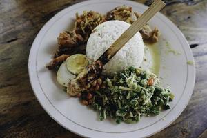 nasi campur ayam betutu. balinesisches Brathähnchen gefüllt mit Maniokblättern. begleitet von gedünstetem Reis, Sate Lilit, Jukut Antungan, Lawar Nangka und Sambal Matah. foto