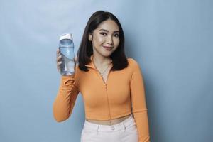 asiatische junge Frau, die nach dem Training eine Flasche Wasser trinkt. foto