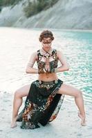schönes Mädchen in Stammes-Fusion-Kostüm, das in einer Pose am Ufer des Strandes steht, Hintergrund des blauen Meeres. foto