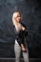 Schönes Mädchen mit blonden Haaren in einem schwarzen Hemd auf dunklem Hintergrund mit Kreideflecken