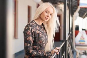 Schöne Frau in Lederjacke mit Blumen, die in der Nähe des Geländers stehen. Frühling. foto