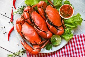 meeresfrüchteteller mit kräutern gewürzen rosmarin zitronensalat salatgemüse, frische krabben auf weißem teller und meeresfrüchtesoße, krabbenkochen gekochtes oder gedämpftes krabbenrot im restaurant - draufsicht foto