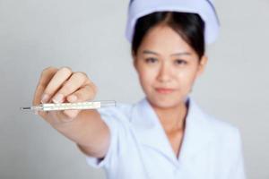 junge asiatische Krankenschwester zeigen Thermometerfokus am Thermometer