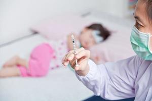 Ärztin bereitet eine Injektion für ein kleines asiatisches Mädchen vor
