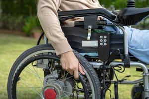 asiatische Patientin auf elektrischem Rollstuhl mit Joystick und Fernbedienung auf der Krankenstation, gesundes, starkes medizinisches Konzept foto