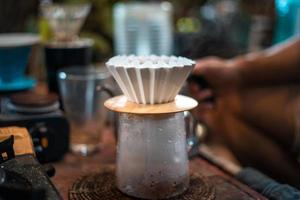 Tropfkaffee, Barista gießt Wasser auf Kaffeesatz mit Filter foto