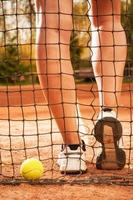 Tenniskonzept mit Ball, Netz und Frauenbeinen