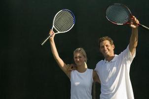 Tennispartner, die Schläger zum Sieg erheben foto