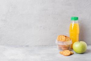 Cracker und frischer Apfel- und Orangensaft auf dem grauen Tisch. Platz kopieren. konzept schulfrühstück. foto