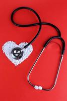Herz von Pillen und Stethoskop auf rotem Hintergrund foto
