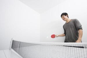 asiatischer mittlerer erwachsener Mann, der Tischtennis spielt foto