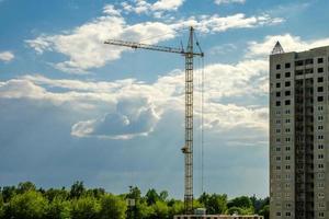 turmkräne und unvollendete mehrstöckige hoch in der nähe von gebäuden im bau an sonnigen abenden mit schönen wolken foto