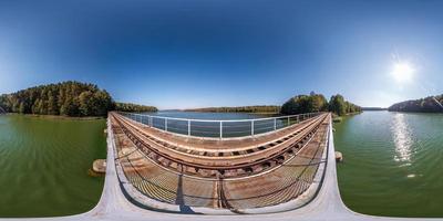 volles sphärisches 360-Grad-Winkelansichtspanorama auf Stahlrahmenkonstruktion einer riesigen Eisenbahnbrücke über den See in gleichwinkliger Projektion. vr ar-Inhalt foto