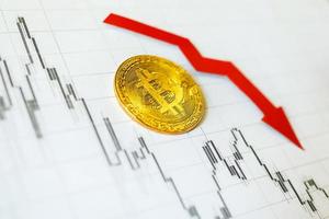 Abschreibung von virtuellem Geld Bitcoin. roter pfeil und goldene bitcoin auf dem papierforex-chart-index-rating sinken auf dem hintergrund des börsenmarktes. konzept der abschreibung von kryptowährung. foto