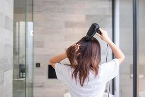 junge frau, die zu hause oder im hotel einen fön verwendet. Frisuren und Lifestyle-Konzepte foto