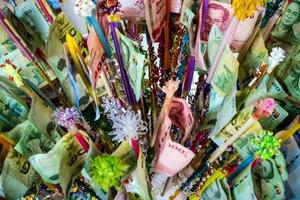 thailändische Banknoten, die am Ende des Holzes festgeklemmt sind, mit farbigem Papier verziert und zusammengebunden sind, um sich darauf vorzubereiten, sie dem Tempel zu geben foto