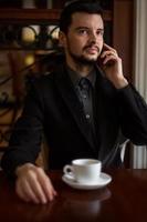 hübscher Geschäftsmann, der in einem Café am Telefon spricht foto