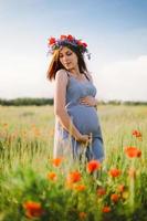 schwangere glückliche Frau in einem blühenden Mohnfeld