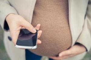 schwangere Frau, die per Handy anruft foto
