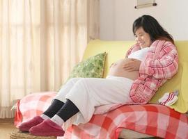 schwangere Frau sitzt auf dem Sofa foto