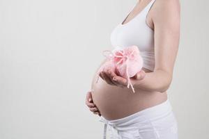 schwangere Frau, die rosa Babyschuhe in ihren Händen hält foto