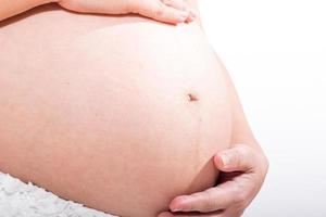 schwangere Frau streichelt ihren Bauch über weißem Hintergrund