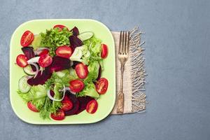 Gesunder Rote-Bete-Salat in grüner Schüssel auf grauem Holzhintergrund. foto