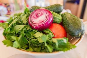 gewaschenes gemüse - gurken, tomaten, rote zwiebel und petersilie in einem teller, fertig zum zerkleinern für den salat foto