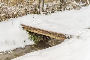 verschneite Brücke über einen mit Eis bedeckten Bach foto