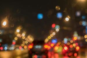 Defokussierte Straße mit Lichtern durch nasses Autofenster foto