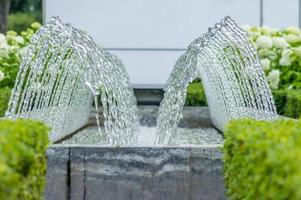 Brunnen mit Blumenbeet aus blühender weißer Hortensie foto