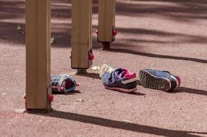 Auf dem Spielplatz liegen zwei Paar Kinderturnschuhe foto