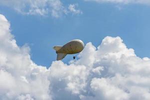 Weißes Luftschiff eines weichen Systems mit Stabilisatoren und einem Motor schwebt am Himmel foto