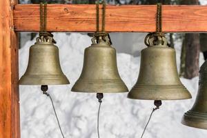 eine Reihe traditioneller orthodoxer Glocken unterschiedlicher Größe, die am Holzständer hängen foto