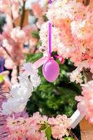 Violettes Osterei, das blühenden Apfelbaumzweig zur Dekoration im Freien überreicht foto