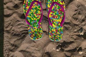 Mehrfarbige Flip-Flops auf Sand mit gezeichneter Herzform. Begriff Urlaub foto